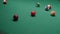 Multicolored billiard balls roll on the green table surface. Close up