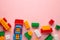 Multicolored blocks of the children`s constructor lie on a pink background