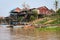 Multicolored boats moored at the original houses on poles by the river