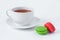 Multicolored cakes macarons and a cup of tea on a saucer