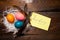 Multicolored chicken, painted eggs for the Easter holiday in nest with feathers and leaf with the inscription Happy Easter on awoo