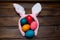 Multicolored chicken, painted eggs for the Easter holiday on a wooden outline background with pink rabbit ears