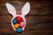 Multicolored chicken, painted eggs for the Easter holiday on a wooden outline background with pink rabbit ears