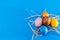 Multicolored easter eggs in hay on blue background, close up. Easter, spring, holidays, culture and religion concept