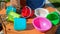 Multicolored empty clean plastic tableware on a wooden background, outdoors, on a sunny summer day