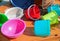 Multicolored empty clean plastic tableware on a wooden background, outdoors, on a sunny summer day