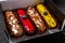 Multicolored glazed eclairs decorated with blueberries are in a cardboard package