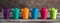 Multicolored holi powders in cups in a row on a wooden dark table, banner. Holi color festival. Selective focus