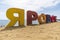multicolored inscription Yarovoe in russian language on the yellow sand on background of the lake and tourists. Yarovoe name of