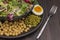 Multicolored leafy vegetables mix, chickpeas, mung bean, egg and fork in black plate