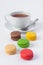 Multicolored macarons and a cup of tea on a white background