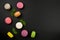 Multicolored macaroons on a black background, top view. Mint leaves next to macaroon. Flat lay