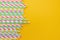 Multicolored party drinking straws on yellow background,