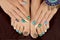 Multicolored pedicure and manicure with rhinestones on oval long female nails.