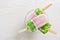 Multicolored pink-green ice cream on a stick. White background, top view, copy space.