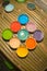 Multicolored plastic cups with paints on bamboo table background.