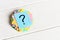 Multicolored question marks written reminders tickets on white wooden background