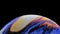 Multicolored rainbow colors of a single soap bubble that looks like a fantasy planet isolated against a black background