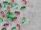 Multicolored red and green gelatin transparent capsules with oily drug on gray background with copy space. mint and berry candies