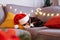 Multicolored relaxed cat lying on a gray sofa in a Santa's hat with blurred Christmas decor composition on the