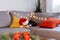 Multicolored relaxed cat lying on a gray sofa in a Santa's hat with blurred Christmas decor composition on the