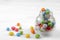 Multicolored round candy in a glass jar on a white background.