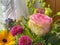 Multicolored spring flower bouquet with a pink rose on a windowsill with white curtain, vintage styl