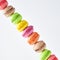 Multicolored stacked macarons on white background showing diagonal line, closeup view