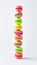 Multicolored stacked macarons on white background, vertical banner