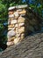 Multicolored stone chimney and weathered gray wood roof shingles