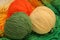 multicolored three balls of wool lie on a knitted tablecloth