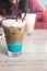 A multicolored, three layered opaque coffee in a glass with ice