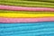 Multicolored towels stacked on a shelf.