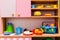 Multicolored toy dishes, vegetables and fruits made of plastic stand on a children toy kitchen.