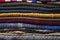 Multicolored, warm, knitted, bright woolen scarves are stacked in each other in a pile, ready for the onset of a cold winter.