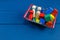 Multicolored wooden blocks, cars, train in basket on blue background. Trendy eco-friendly puzzle toys.