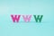 Multicolored wooden letters WWW on a pale blue background