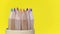 Multicolored wooden pencils rotating on a yellow background.