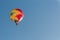 Multicoloured hot air balloon, blue sky.