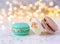 multicoloured macarons with cream and almonds on white surface, golden bokeh effect behind