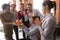 Multicultural employees in party hats congratulate female with birthday cake