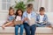 Multicultural group of focused children reading books while sitting on sofa