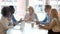 Multicultural professional team colleagues having conversation sit at conference table