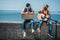 multicultural young men with cardboard and guitar resting on parapet while hitchhiking