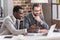 multiethnic businessmen smiling and looking at laptop screen