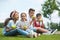 Multiethnic children eating green apples while sitting together on green grass