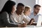 Multiethnic colleagues seated in coworking room discuss new corporate app