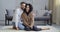 Multiethnic couple caucasian bearded man and afro american woman hugging on floor at home in living room barefoot two
