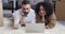 Multiethnic couple caucasian man and african american woman husband and wife lying on floor looking at laptop screen
