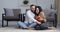 Multiethnic couple of newlywed lovers sitting on floor at home celebrating new year christmas valentine`s day. Afro